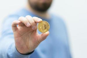 Mann hält Bitcoin in der Hand foto