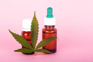 Hanföl für medizinische Zwecke, Flaschen mit medizinischem Cannabisextrakt auf rosa Hintergrund
