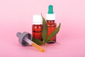 Hanföl für medizinische Zwecke, Flaschen mit medizinischem Cannabisextrakt auf rosa Hintergrund