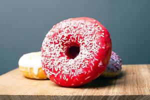 köstlich leckerer roter Donut mit weißem Pulver auf einem Holzständer auf grauem Hintergrund foto