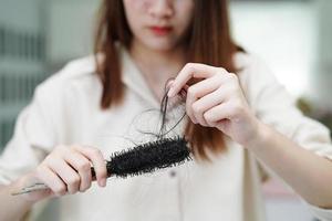 asiatische frau hat ein problem mit langem haarausfall in der hand. foto