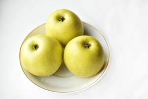 drei grüne Äpfel auf einem weißen Teller foto