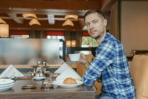 Porträt von Mann mit Kaffee und Frühstück im Restaurant von Luxus Hotel foto