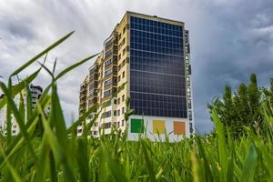 Solar- Paneele auf das Mauer von ein mehrstöckig Gebäude auf Grün Bäume Hintergrund. verlängerbar Solar- Energie foto