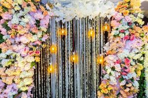 bunt künstlich Blumen mit dekorativ Antiquität Edison Stil Glühfaden Licht Glühbirnen hängend auf Hochzeit Bühne Dekoration. foto
