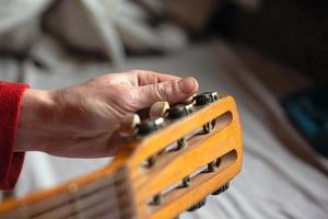 Musikerhand dreht die Melodien der Gitarre und stimmt das Instrument foto