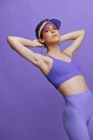 sportlich Mode Frau posieren im ein lila Sport passen zum Yoga und ein transparent Deckel auf ein lila Hintergrund einfarbig foto
