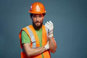 ein Mann im ein Arbeit Uniform ist ein Konstruktion Ingenieur. Industrie Fachmann Orange schwer Hut foto