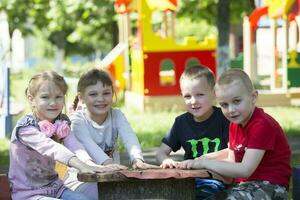 ein Gruppe von Kinder von Kindergarten zum ein gehen. sechs Jahr alt Jungs und Mädchen abspielen zusammen. foto