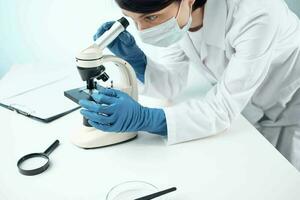 weiblich Arzt im medizinisch Maske Mikroskop Technologie Forschung foto
