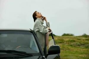 schön Frau mit rot Haar im ein Sweatshirt in der Nähe von das Auto Natur weiblich entspannend foto