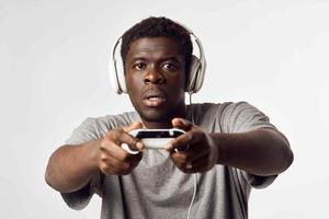 ein Mann von afrikanisch Aussehen im Kopfhörer mit ein Gamepad im seine Hände Theaterstücke Video Spiele Technologie foto