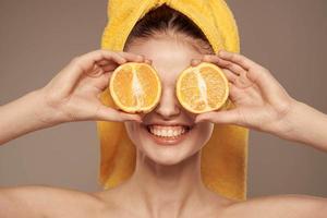 Frau im ein Gelb Handtuch auf ihr Kopf Orangen Nahansicht Beige Hintergrund foto