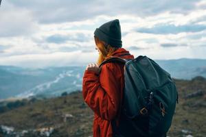 energisch Frau im warm Kleider mit Rucksack Reise Tourismus Berge Landschaft zurück Aussicht foto