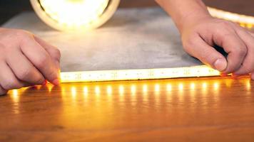 Hände installieren eine leuchtende LED-Streifen-Nahaufnahme auf einer Holzoberfläche foto