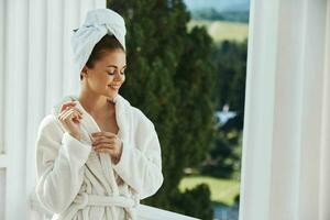 schön Frau mit ein Handtuch auf meine Kopf im ein Weiß Bademantel bleiben auf das Balkon im ein Hotel Lebensstil foto