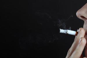 Mann raucht eine Zigarette auf einem dunklen Hintergrund Nahaufnahme mit Kopierraum