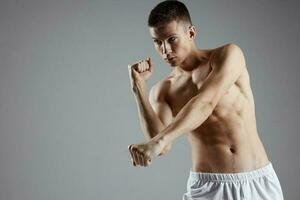 Boxer mit gepumpt oben Arm Muskeln auf ein grau Hintergrund und Abs Würfel auf seine Bauch foto