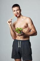 süß Kerl mit ein Muskel gekrönt Körper Teller Salat gesund Essen isoliert Hintergrund foto