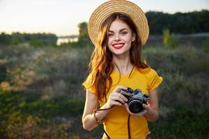 Frau Fotograf mit ein Kamera im ihr Hände Lächeln rot Lippen Hut frisch Luft foto