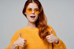 ziemlich Frau im ein Gelb Sweatshirt Mode Brille Licht Hintergrund foto