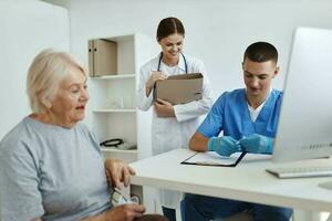 ein Alten Frau Sitzung beim ein Arzt geplanter Termin mit ein Krankenschwester Behandlung foto