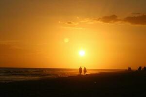 Strand Sonnenuntergang mit etwas Wolken Menschen Silhouette foto