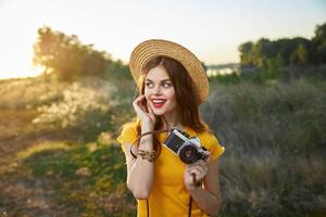 ziemlich Frau mit ein Kamera im ihr Hände auf Natur aussehen zu das Seite Lächeln rot Lippen Sommer- foto