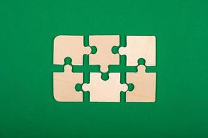 hölzernes Puzzle auf grünem Hintergrund