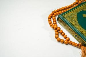 das heilig al Koran mit geschrieben Arabisch Kalligraphie Bedeutung von al Koran und Rosenkranz Perlen oder tasbih auf Weiß Hintergrund mit Kopieren Raum. foto