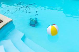Unterwasserroboter, der ein Schwimmbad und einen aufblasbaren Ball schwimmt, der schwimmt foto