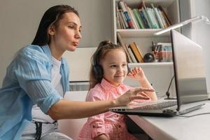 Eltern, die virtuelle Schule auf Laptop für Tochter einrichten foto