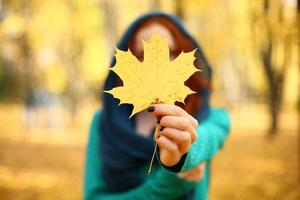 Mädchen, das ein gelbes Ahornblatt im Herbst hält. Herbstblätter. selektiver Fokus. foto