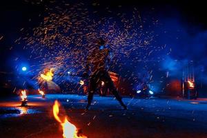 Feuershow, Tanzen mit Flamme, männlicher Meister, der mit Feuerwerk jongliert, Auftritt im Freien, zeichnet eine feurige Figur in den dunklen, hellen Funken in der Nacht. Ein Mann im Anzug führte Tänze mit Feuer foto