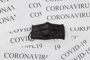 schwarze medizinische Maske auf Coronavirus-Inschriftenhintergrund und covid-19. Konzept zum Schutz vor Umweltverschmutzung, Viren und Grippe. professionelle chirurgische Ausrüstung