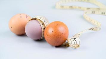 Hähnchen Ei eingewickelt im Messung Band auf Ei auf Weiß Hintergrund. gesund Essen und Diät Konzept. foto
