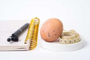 Hähnchen Ei und Messung Band und Stift auf Weiß Hintergrund. Diät Konzept foto