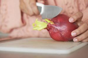 Frauen Schneiden rot Zwiebel mit ein Messer foto