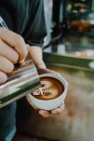 Eingießen von Milch für die Zubereitung von Latte-Art-Kaffee foto