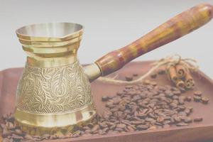 Kupferkaffeekanne oder Ibrik mit Kaffeebohnen und Zimtstangen. auf einem Holzteller. weißer Hintergrund foto