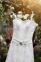 Braut- Hochzeit Kleid hängend auf das Baum Ast im das Garten foto
