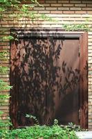 Baum Schatten im das Garten auf Antiquität thailändisch Stil hölzern Fenster auf Backstein Mauer. Jahrgang Konzept. foto