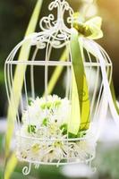 Weiß Vogelkäfig Dekoration mit Rosen und Weiß Blumen hängend Dekoration im Garten zum Hochzeit Zeremonie foto