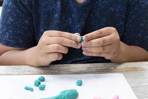 ein autistisch Junge Formen anders Formen von farbig Plastilin bereit durch Eltern beim Zuhause im bestellen zu sich entwickeln verschiedene Aspekte im ihr Sohn welche hat Langsamer Gehirn Entwicklung als normal Kinder. foto