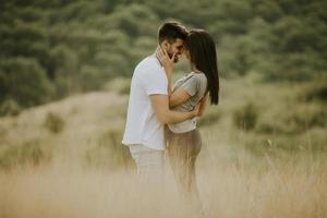 glückliches junges Paar in der Liebe, die durch Grasfläche geht