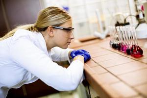 Wissenschaftlerin im weißen Laborkittel analysiert flüssige Proben im biomedizinischen Labor foto
