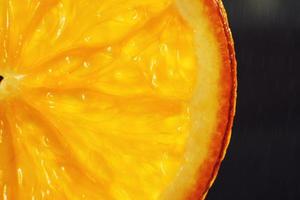 Orange Scheibe Makro mit ein fallen von Wasser Hintergrund . saftig Orange geschnitten Nahansicht auf ein dunkel Hintergrund foto