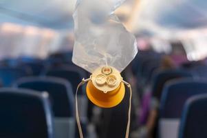 Tropfen der Sauerstoffmaske aus dem Deckenfach im Flugzeug foto