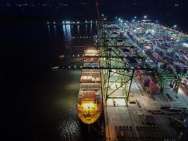 Jakarta, Indonesien 2021 - Luftaufnahme des Be- und Entladens von Containerschiffen im Tiefseehafen, logistischer Import und Export von Frachttransporten mit Containerschiffen auf offener See bei Nacht foto