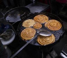 köstlich gereizt Süss Jalebi gebraten im das Kochen schwenken auf ein Straße Essen Markt im Chakbazar, Dhaka, Bangladesch foto